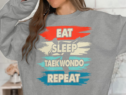 Gray sweatshirt with "Eat Sleep Taekwondo Repeat" text and silhouette.