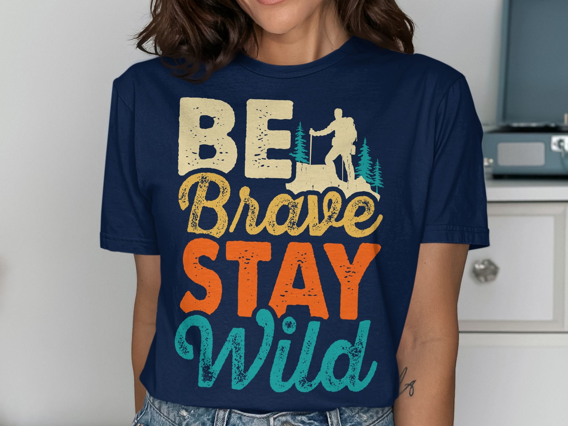 Navy t-shirt with "Be Brave Stay Wild" text and hiking silhouette.