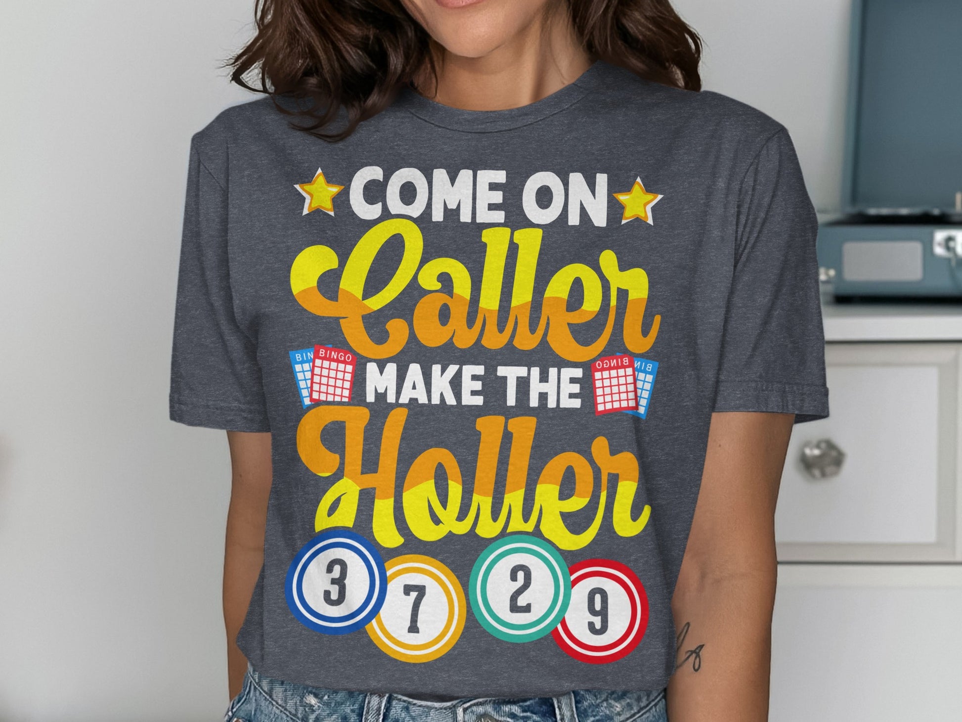 Grey t-shirt with "Come On Caller Make The Holler" and bingo balls.