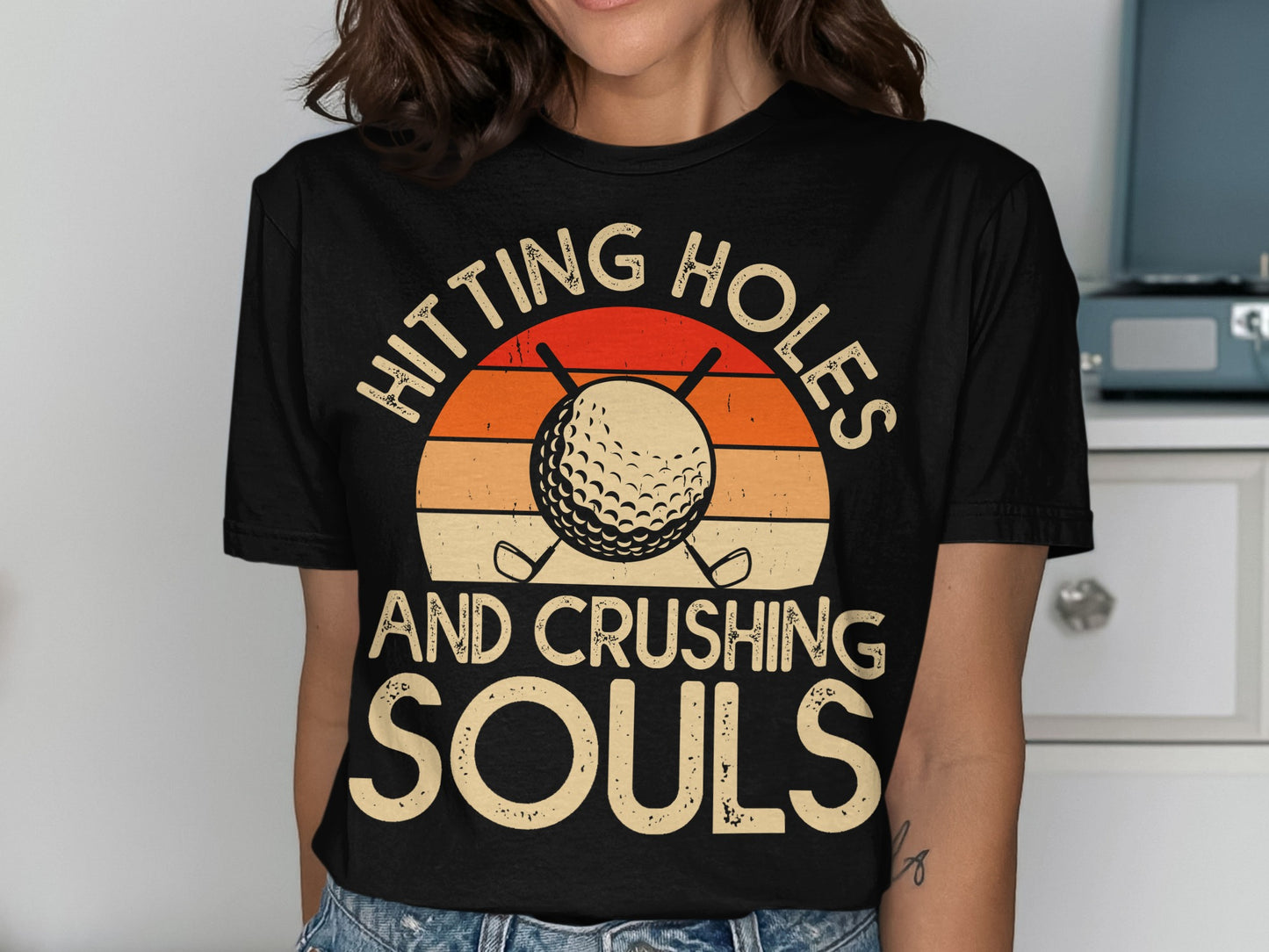 Black t-shirt with "Hitting Holes and Crushing Souls" and golf ball.