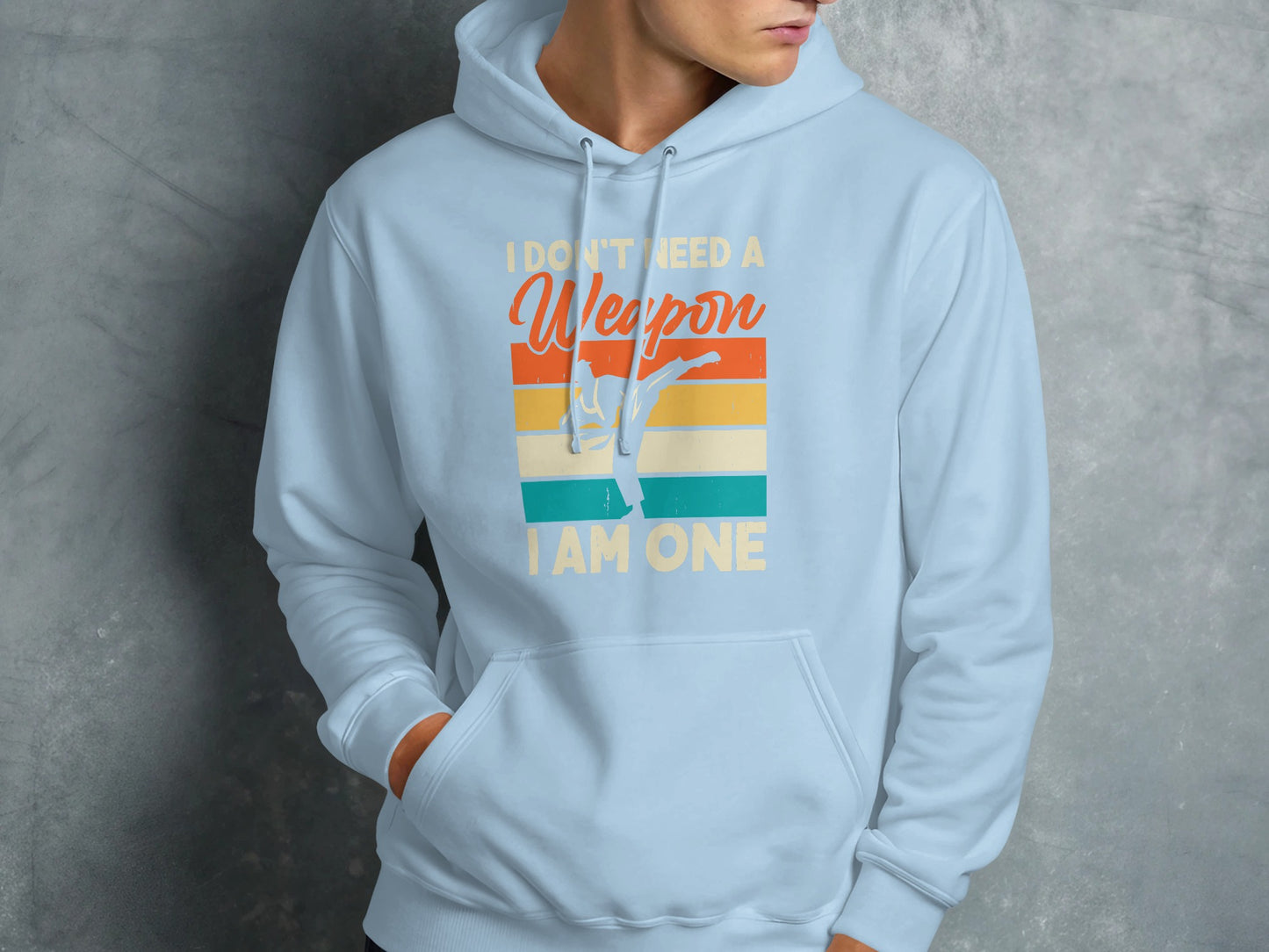 Light blue hoodie with "I Don't Need A Weapon I Am One" text and martial artist graphic.