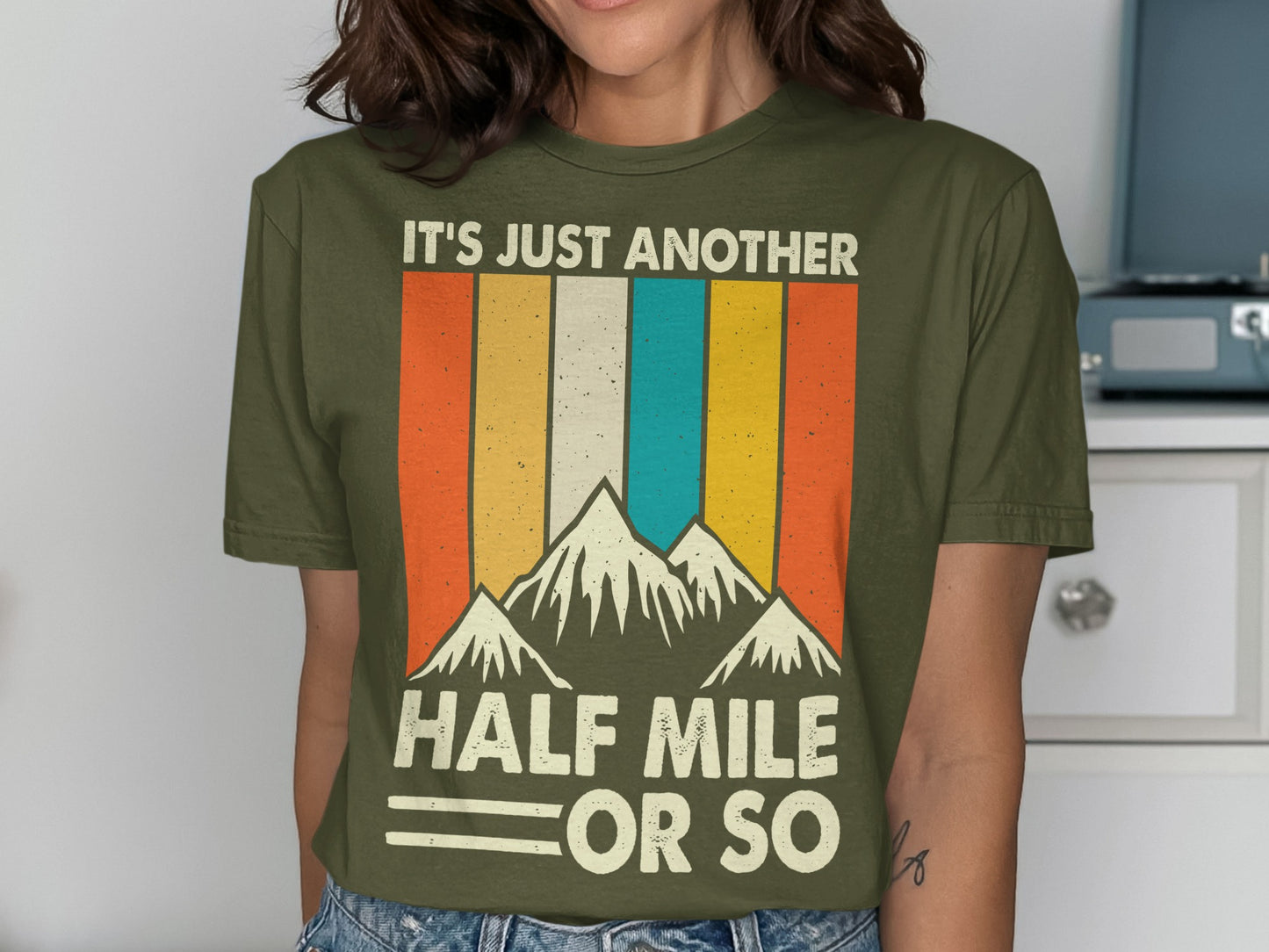 Olive green t-shirt with retro mountains and "It's Just Another Half Mile Or So" text.