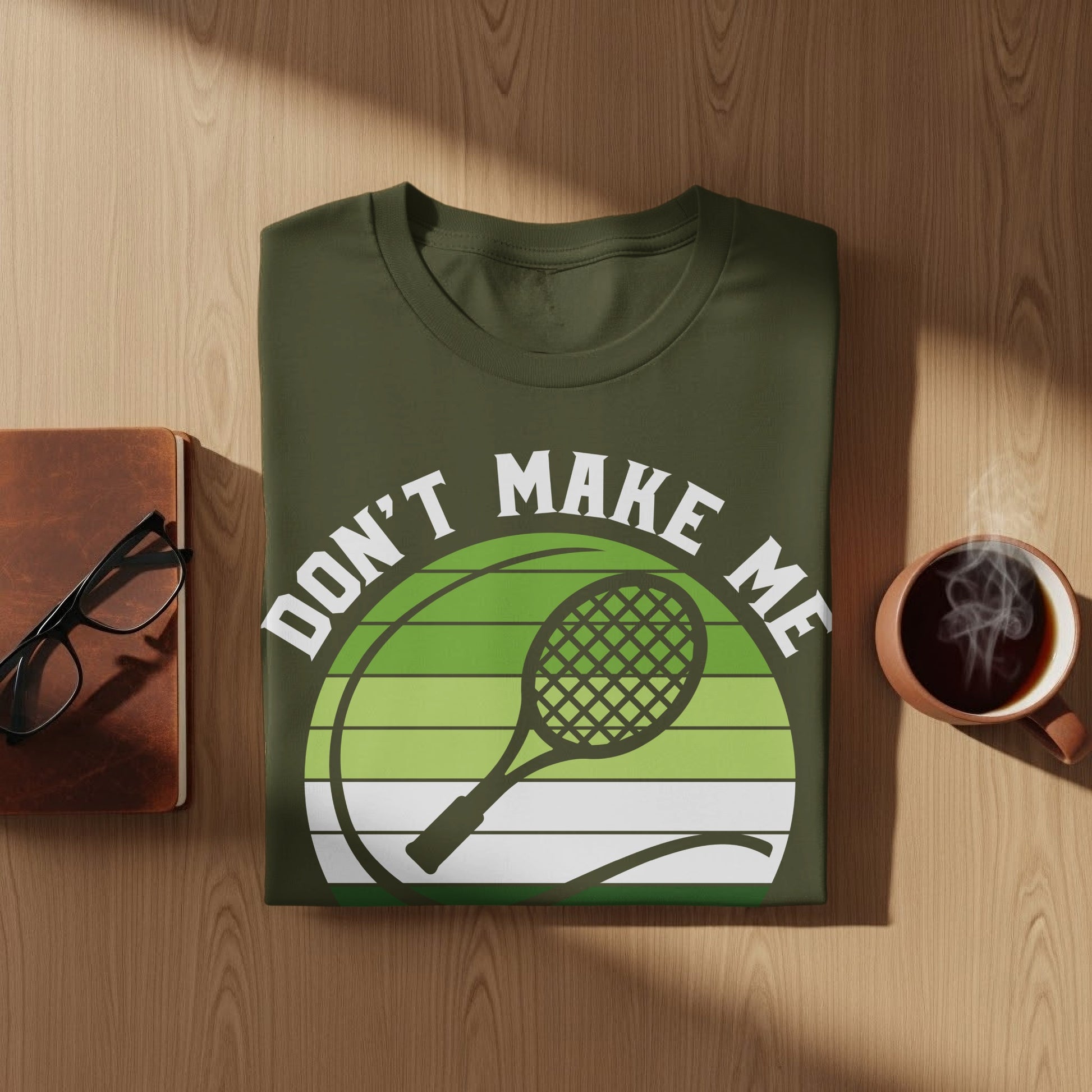 Green t-shirt with "Don't Make Me" and tennis racket graphic.