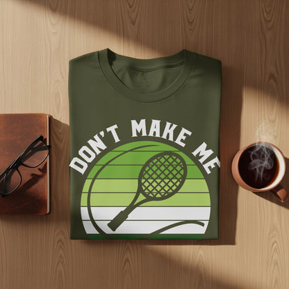 Green t-shirt with "Don't Make Me" and tennis racket graphic.