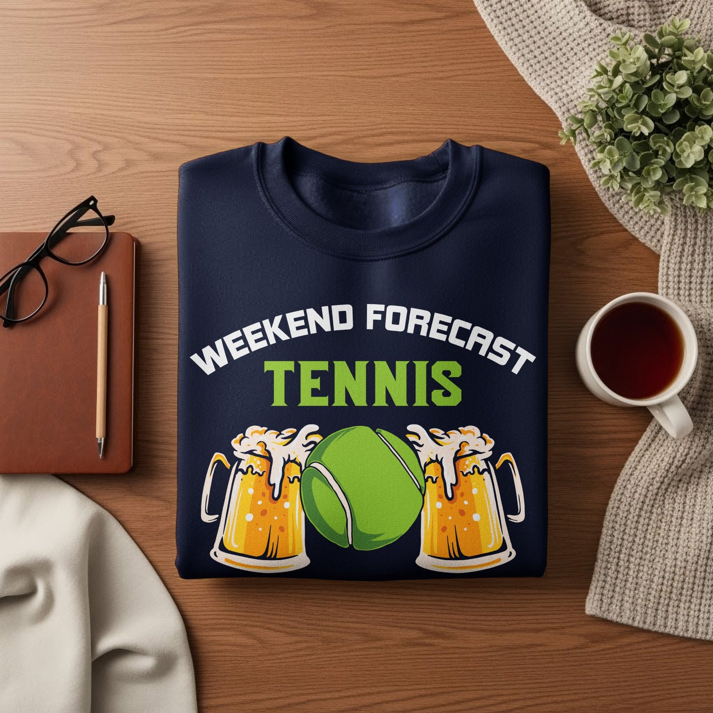 Navy sweatshirt with "Weekend Forecast Tennis" and beer mugs, on a wooden surface.