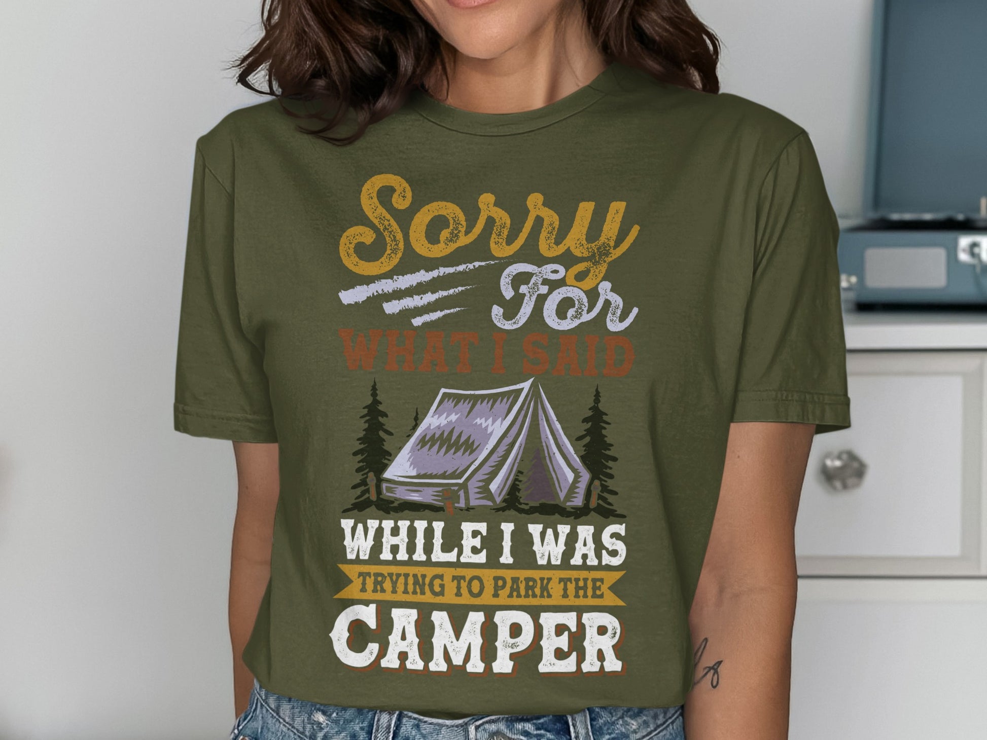 Olive green t-shirt with "Sorry For What I Said While Trying To Park The Camper" text and tent graphic.