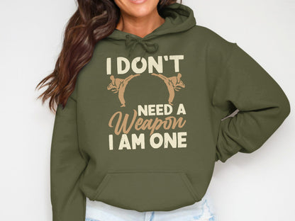 Olive green hoodie with text "I DON'T NEED A WEAPON I AM ONE" and martial arts figures.