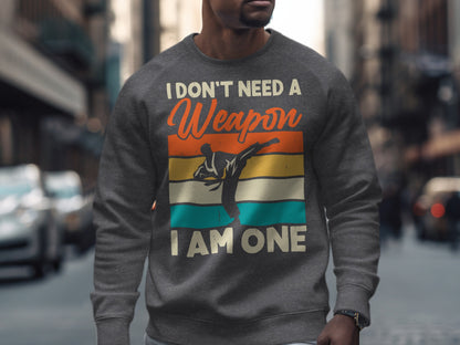 Gray sweatshirt with martial artist silhouette and text: "I DON'T NEED A WEAPON, I AM ONE."