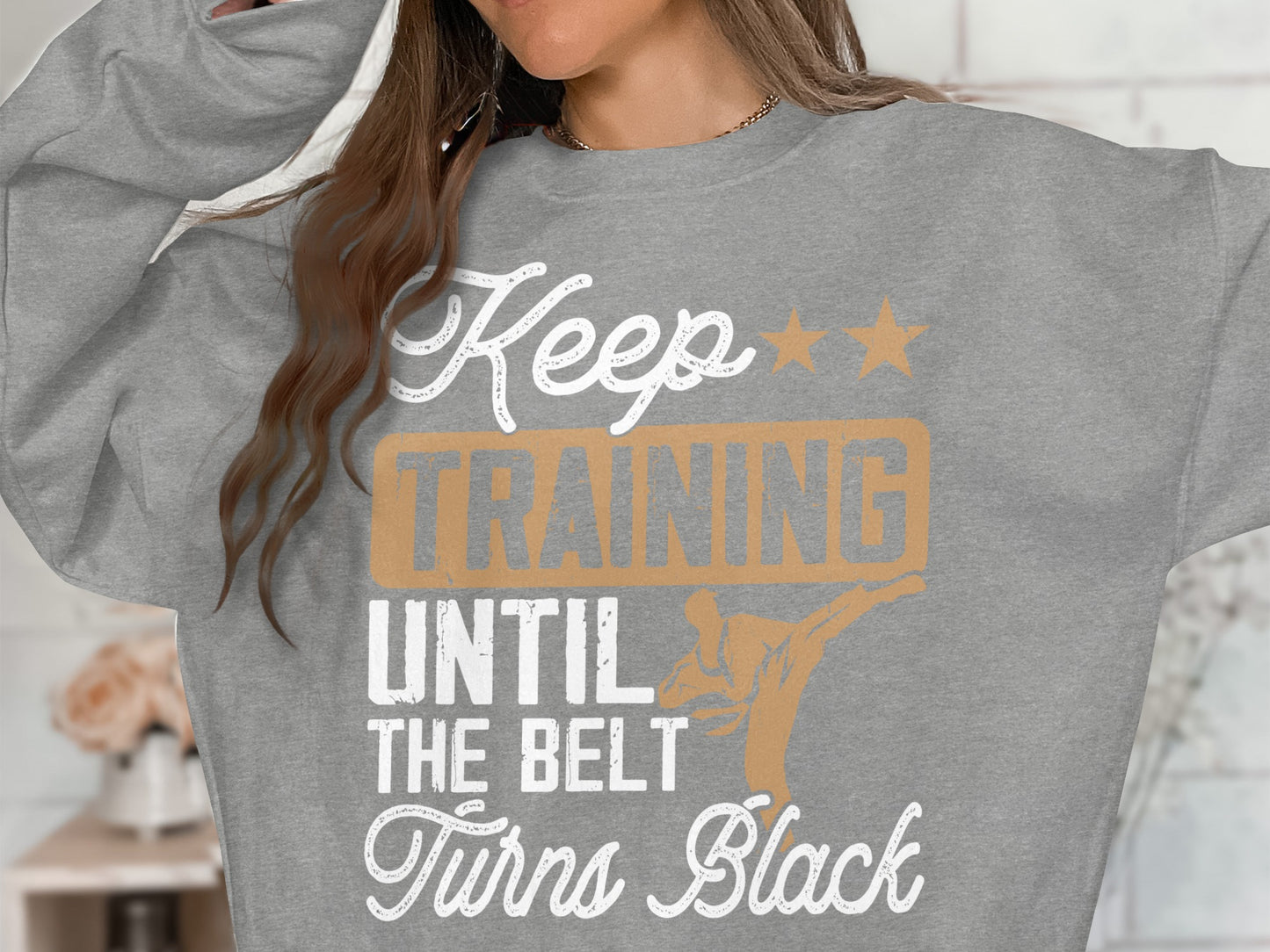 Grey sweatshirt with "Keep Training Until The Belt Turns Black" graphic.