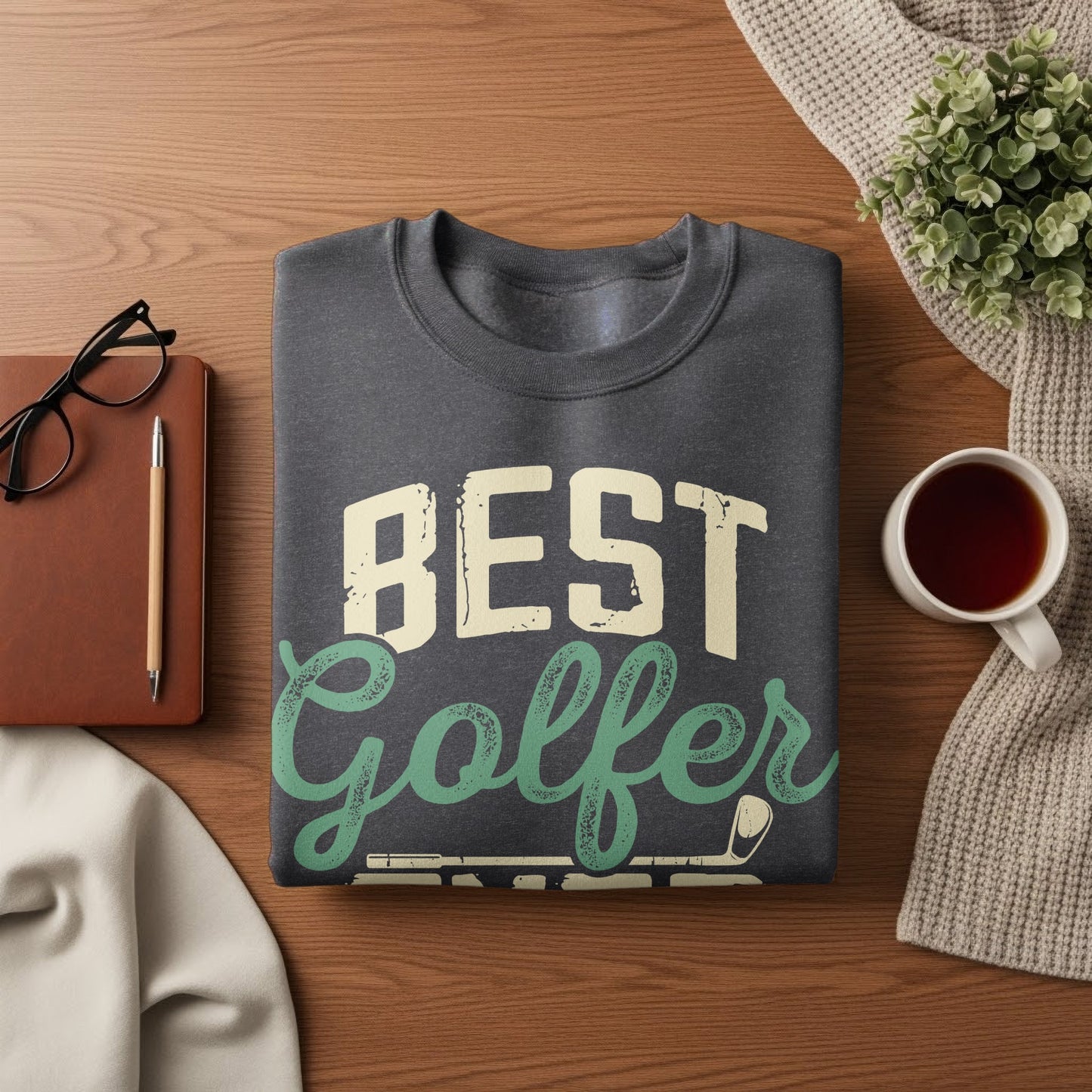 Dark gray sweatshirt with "BEST Golfer" text on a wooden surface.