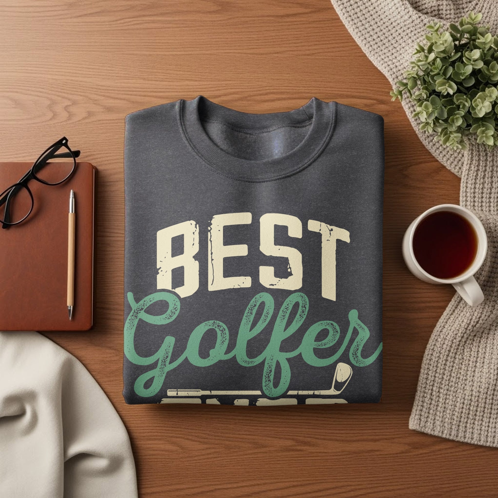 Dark gray sweatshirt with "BEST Golfer" text on a wooden surface.
