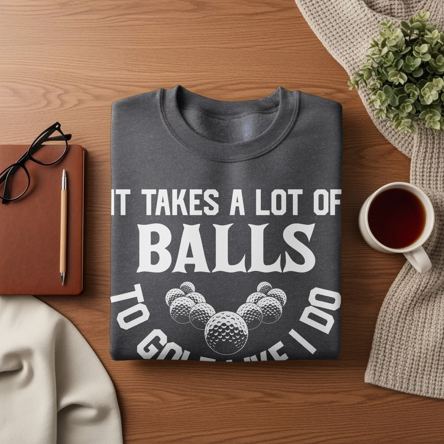 Dark gray crewneck sweatshirt with "IT TAKES A LOT OF BALLS TO GO [golf balls] I DO" graphic.