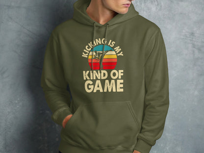 Olive green hoodie with "KICKING IS MY KIND OF GAME" text and retro sunset graphic.