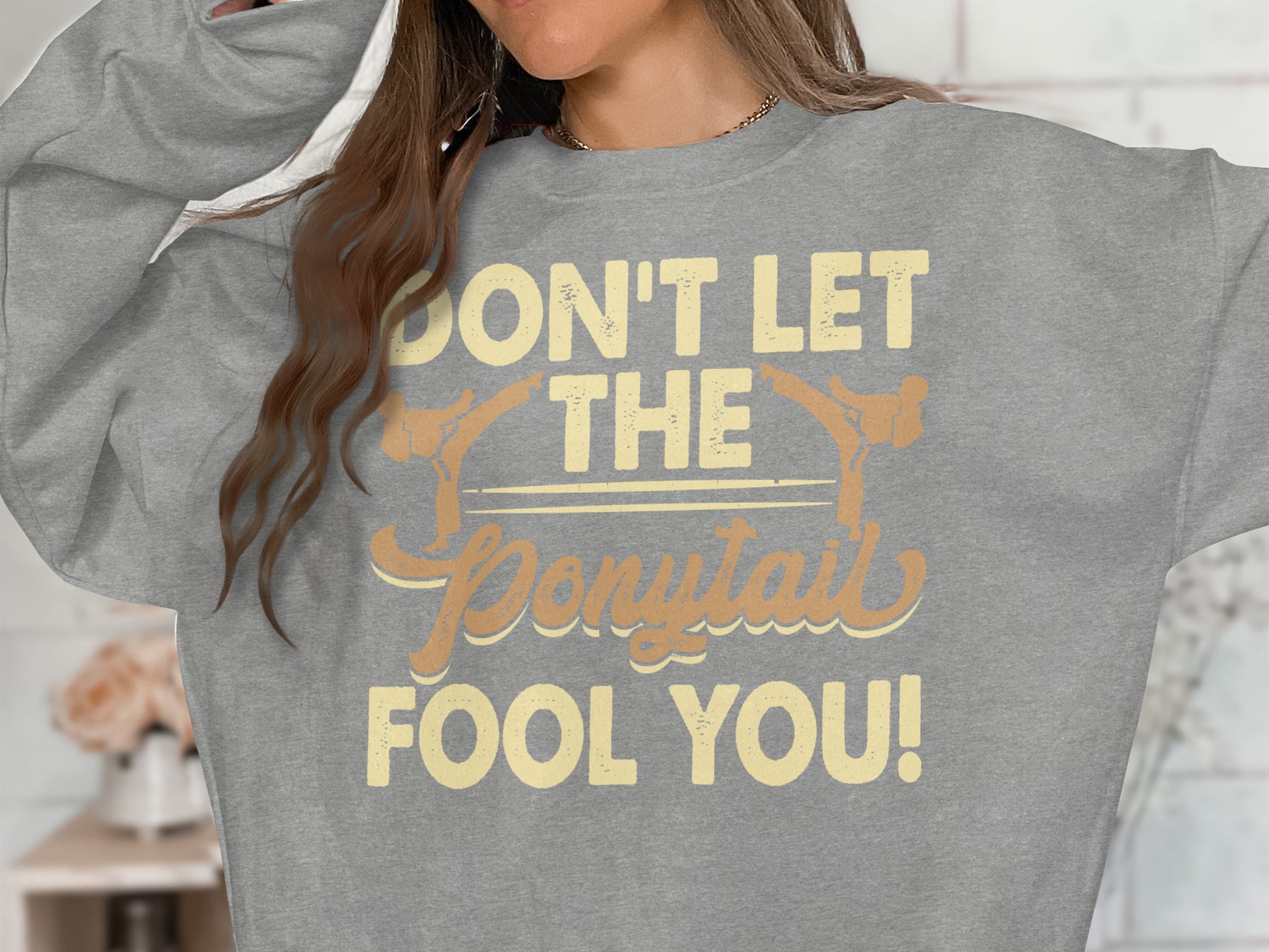 Grey sweatshirt with "Don't Let the Ponytail Fool You!" text.