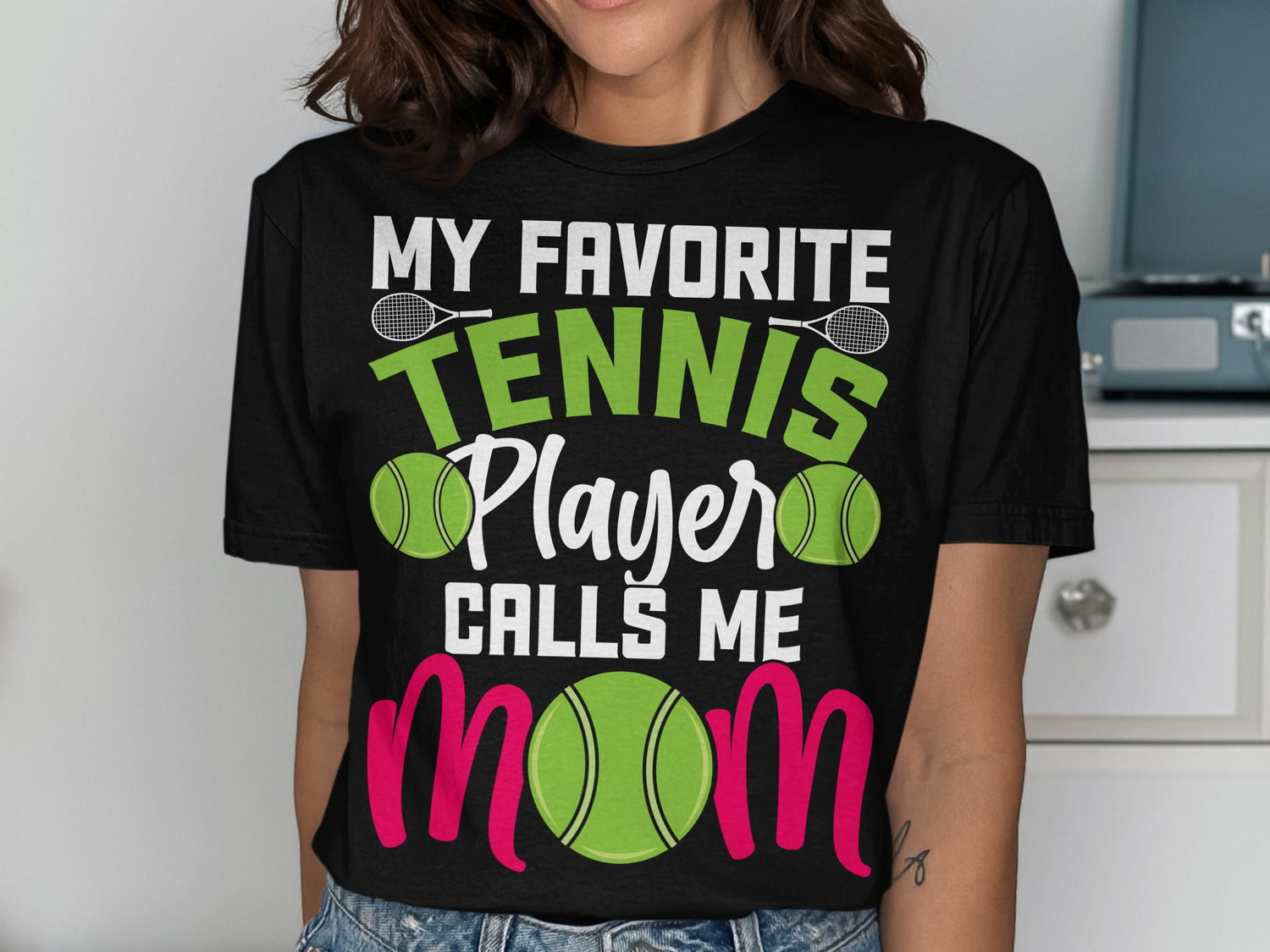 Black t-shirt with "My Favorite Tennis Player Calls Me Mom" text and tennis imagery.