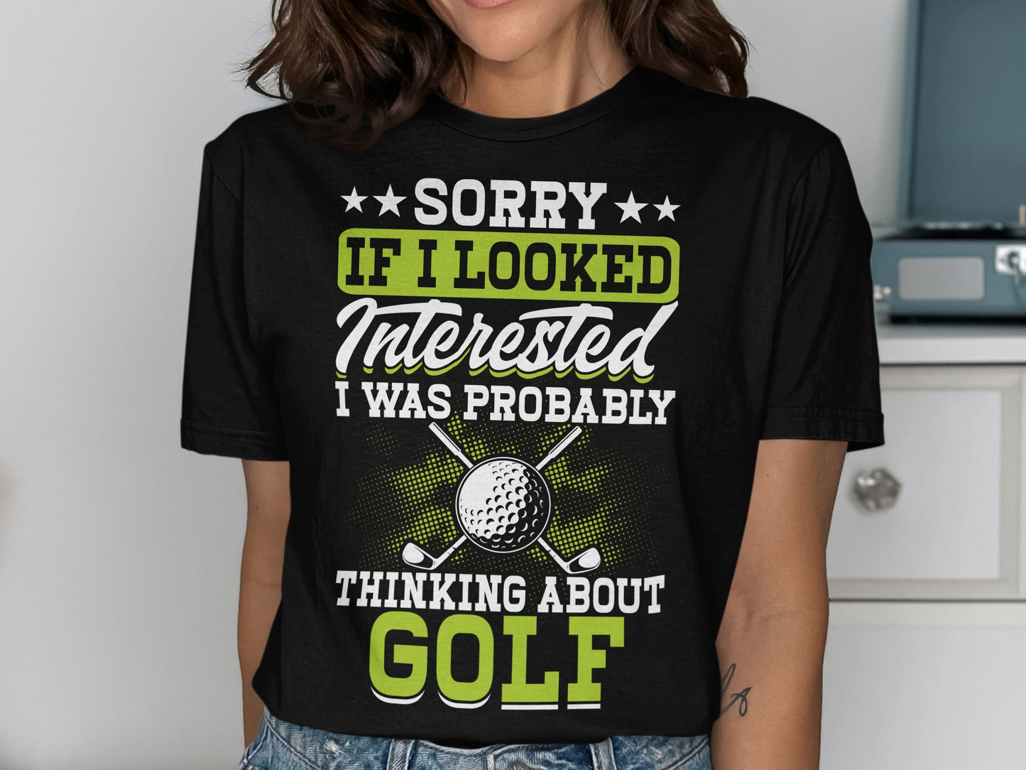 T-shirt with text "Sorry if I looked interested I was probably thinking about golf" and golf clubs.