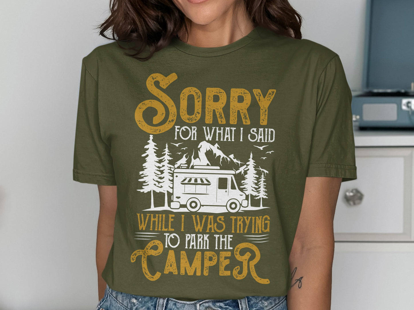 Olive green t-shirt with "Sorry for what I said while I was trying to park the camper" text and camper graphic.