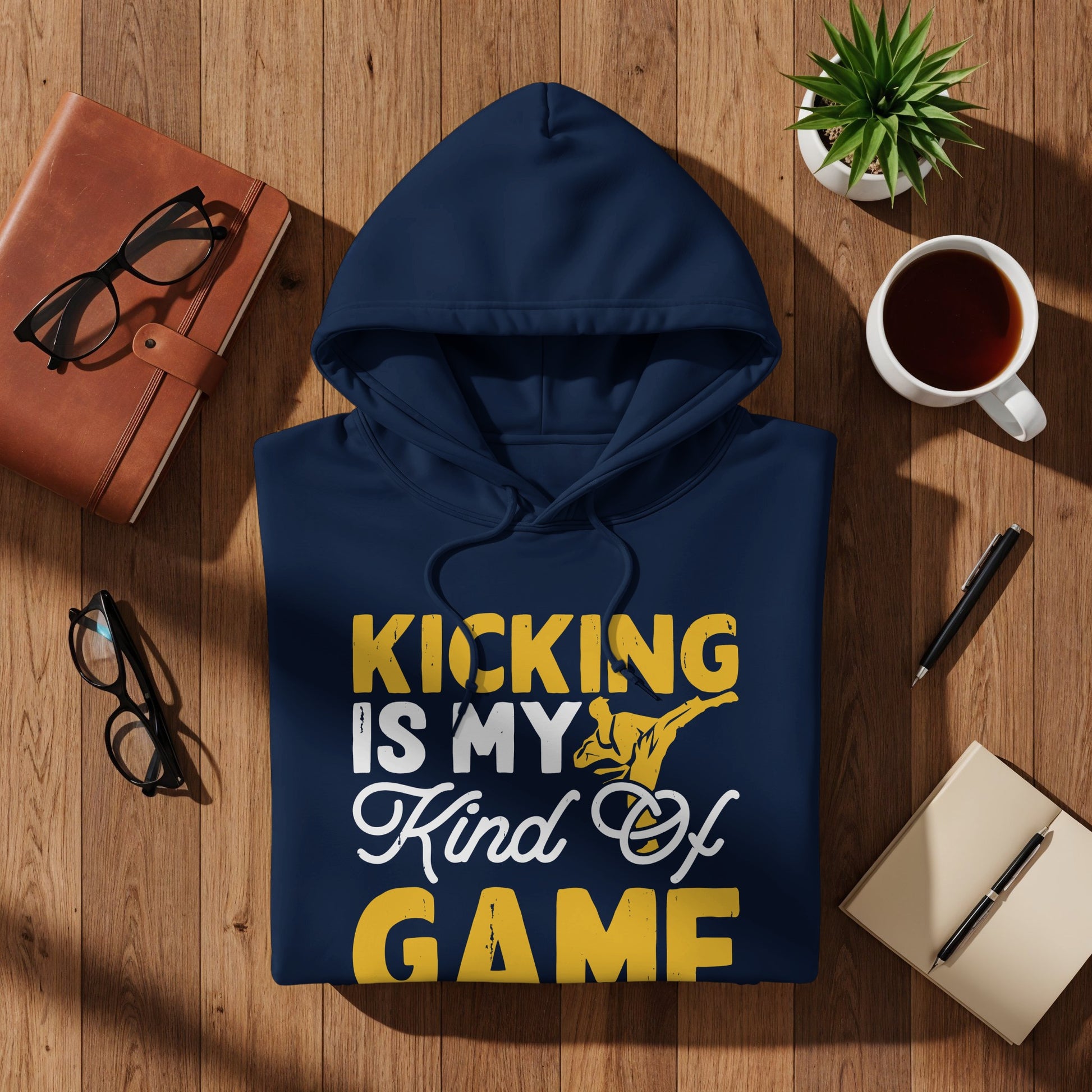 Navy hoodie with "Kicking is my kind of game" graphic on wooden surface.