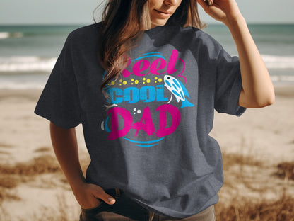 Dark grey t-shirt with "Real Cool Dad" text and fish graphic.