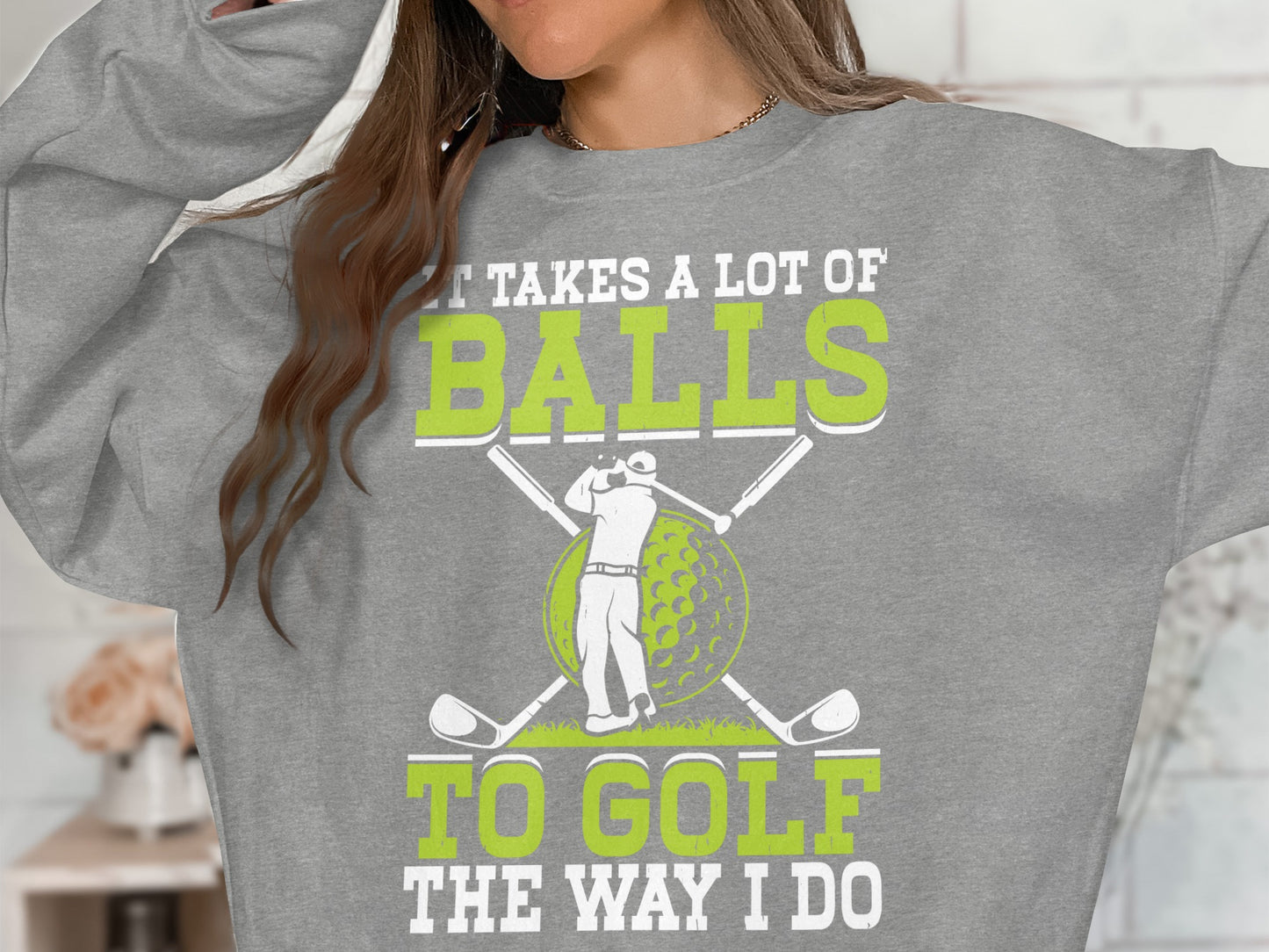 Grey sweatshirt with "It takes a lot of balls to golf the way I do" and golf graphics.