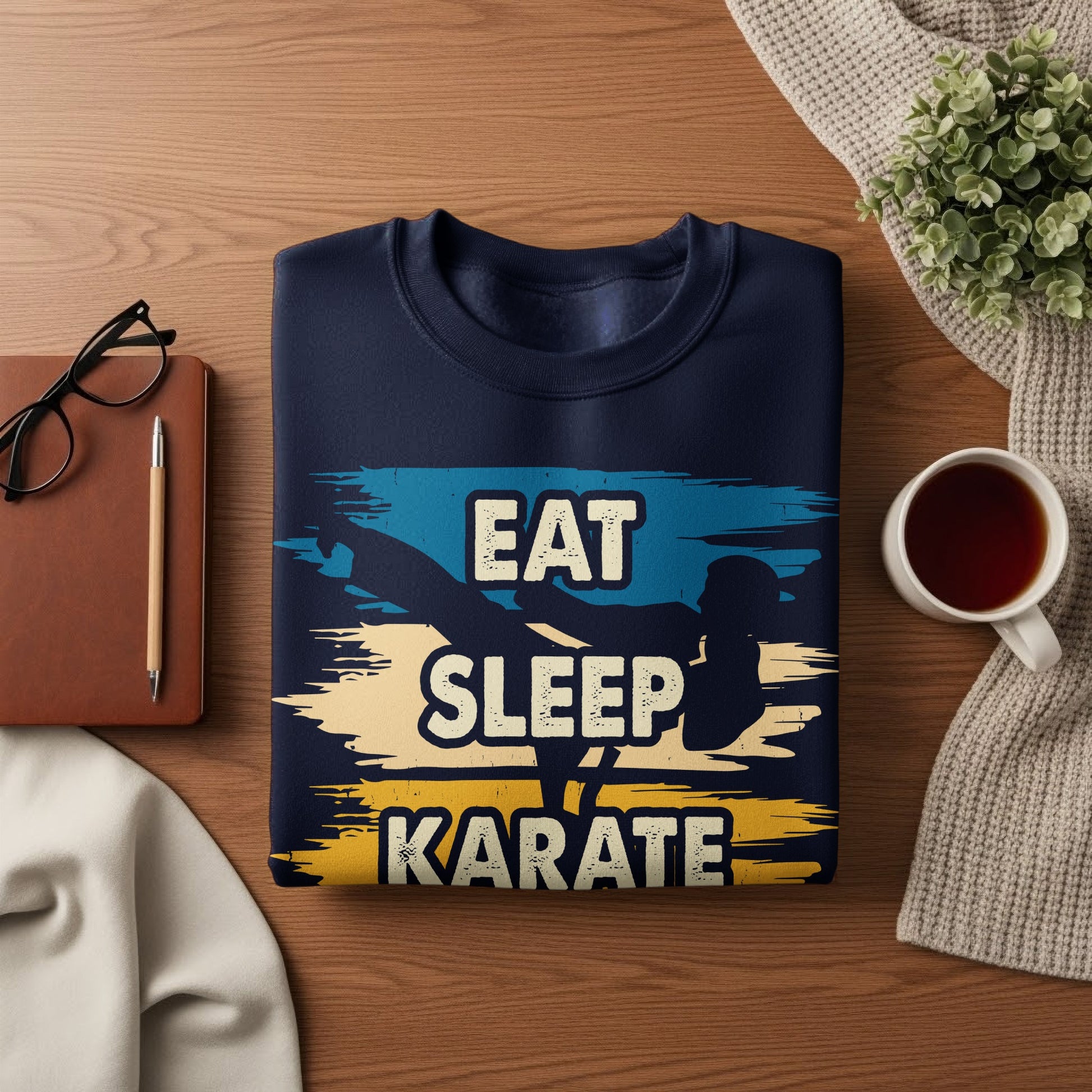 Navy sweatshirt with "Eat Sleep Karate" graphic, on wooden surface with tea and glasses.
