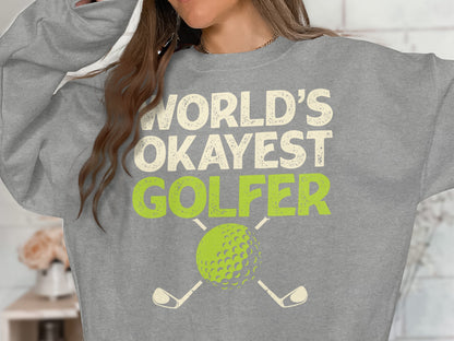 Grey sweatshirt with "World's Okayest Golfer" text and golf ball and clubs graphic.