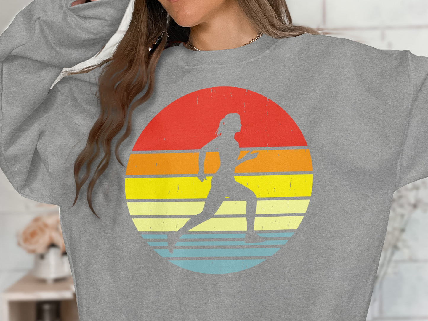 Gray sweatshirt with a runner silhouette against a colorful sunset graphic.