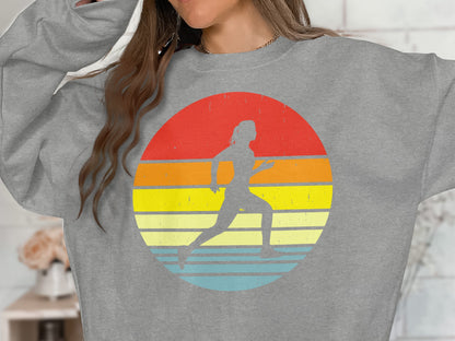 Gray sweatshirt with a runner silhouette against a colorful sunset graphic.