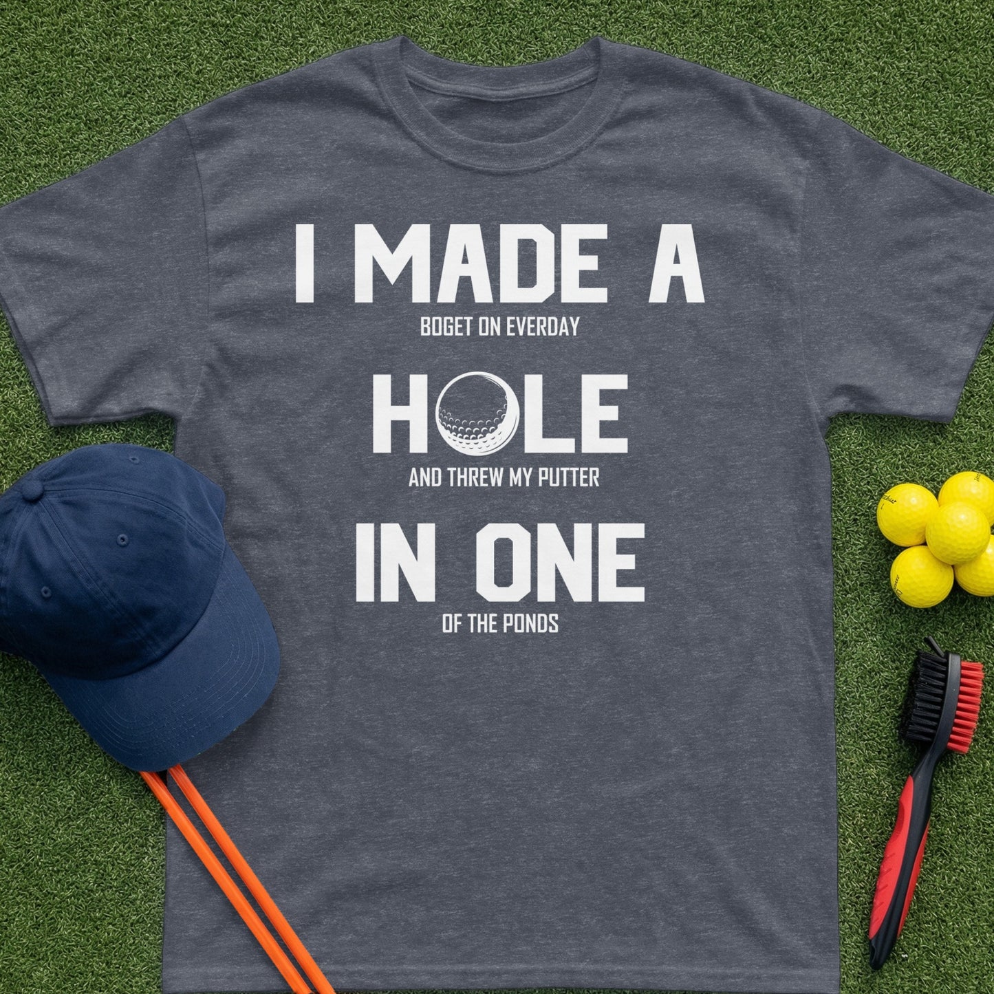 Dark gray t-shirt with "I made a hole in one" text and golf accessories.