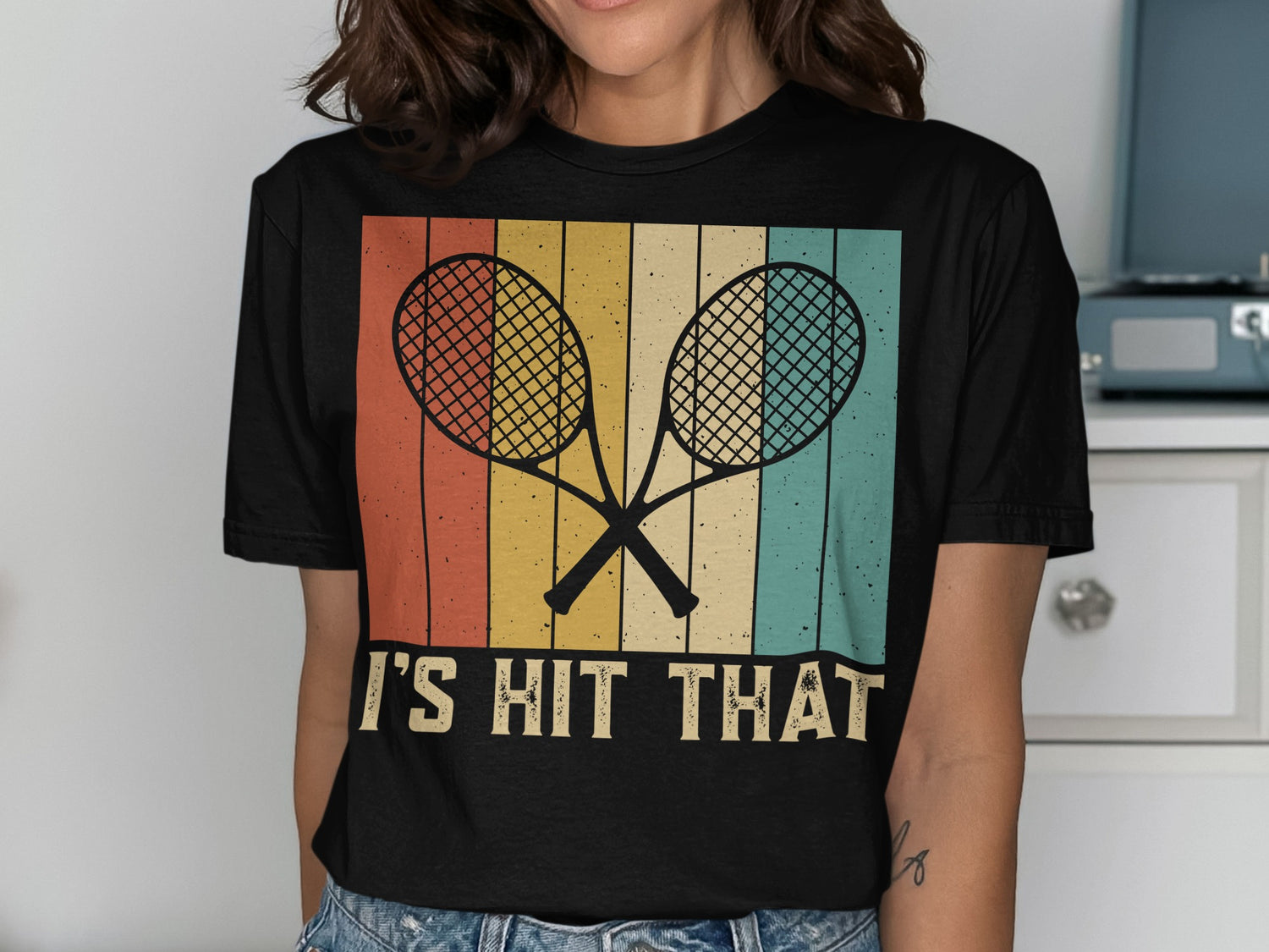 Black t-shirt with crossed tennis rackets and "IT'S HIT THAT" text on striped background.