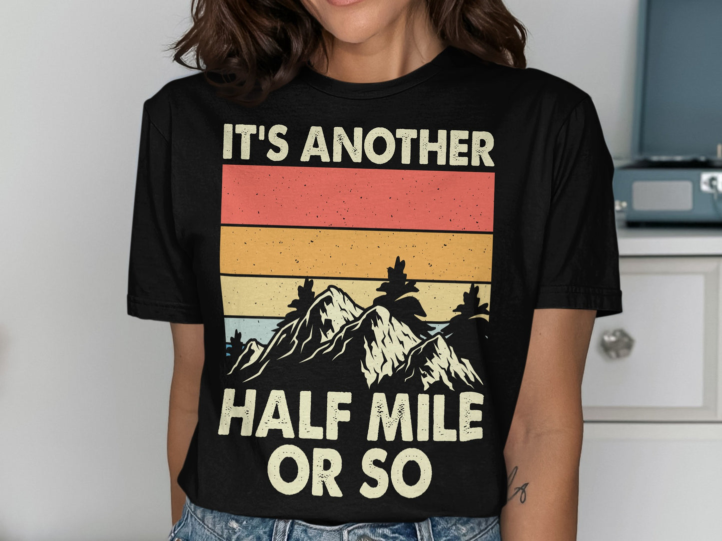 Black t-shirt with "IT'S ANOTHER HALF MILE OR SO" and mountain graphic.