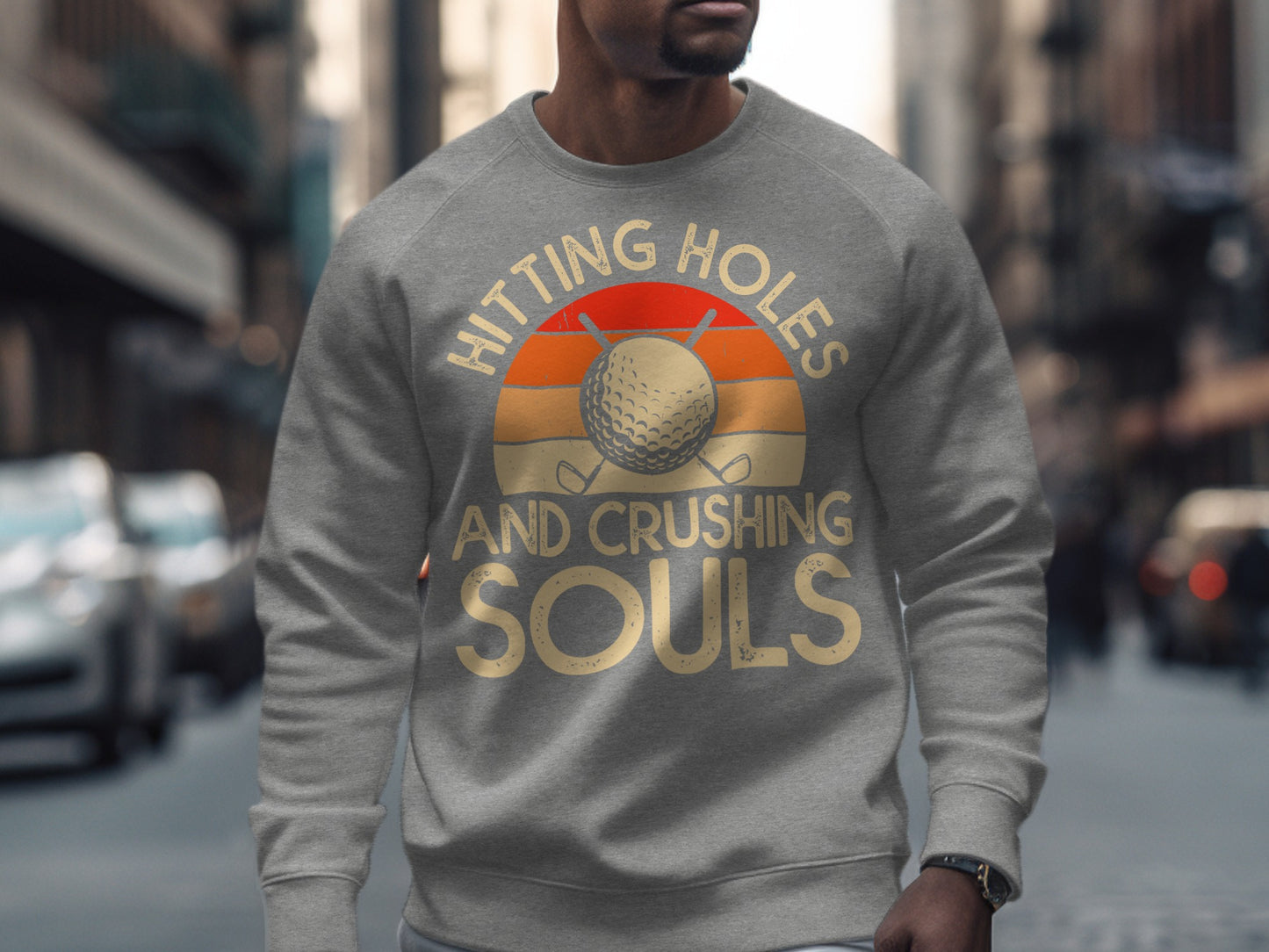 Gray sweatshirt with "Hitting Holes And Crushing Souls" text and golf ball sunset graphic.
