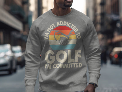Gray sweatshirt with "I'm not addicted to golf, I'm committed" text and golf ball graphic.