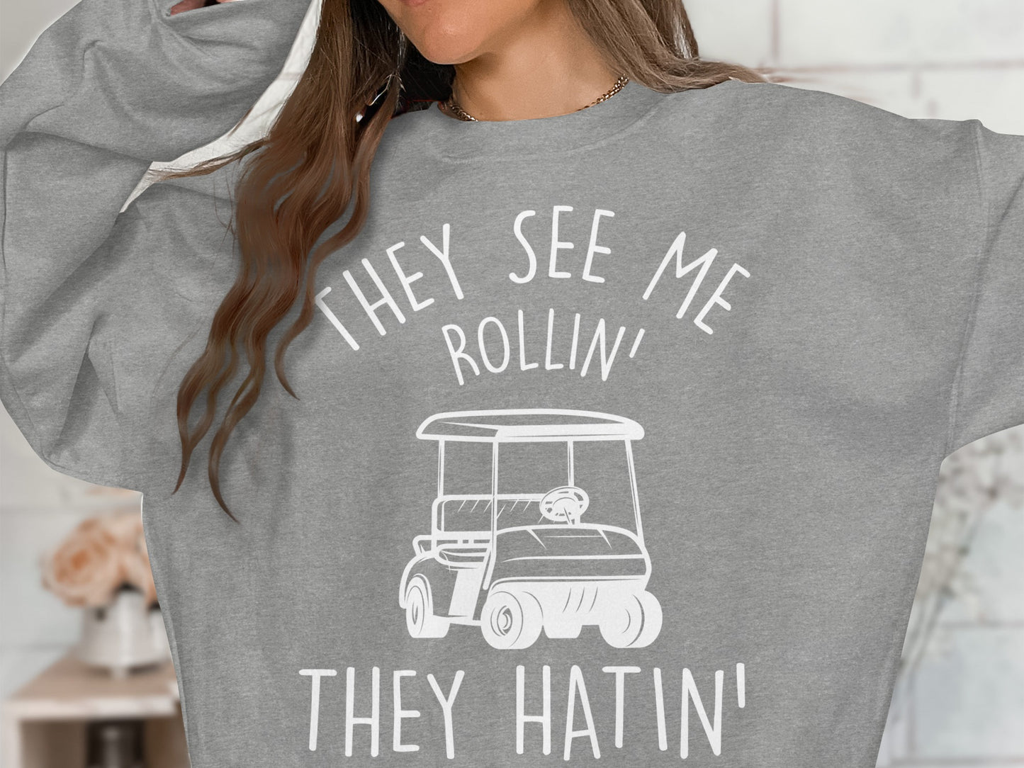 Grey sweatshirt with "They See Me Rollin' They Hatin'" text and golf cart graphic.