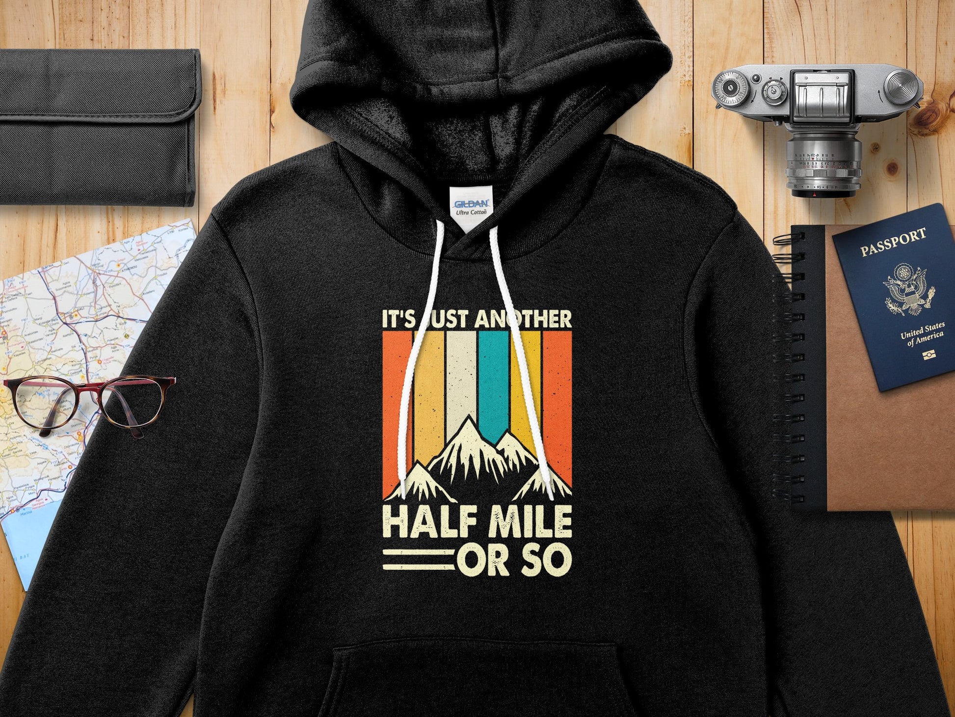 Black Gildan hoodie with "IT'S JUST ANOTHER HALF MILE OR SO" text and mountain graphic.