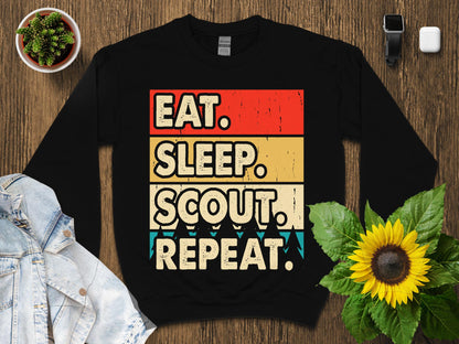Black sweatshirt with "Eat. Sleep. Scout. Repeat." text in retro style.