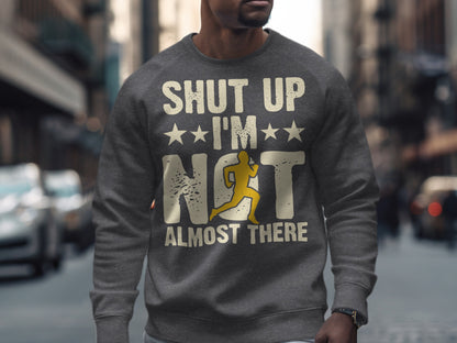 Grey sweatshirt with "Shut Up I'm Almost There" text and running figure.