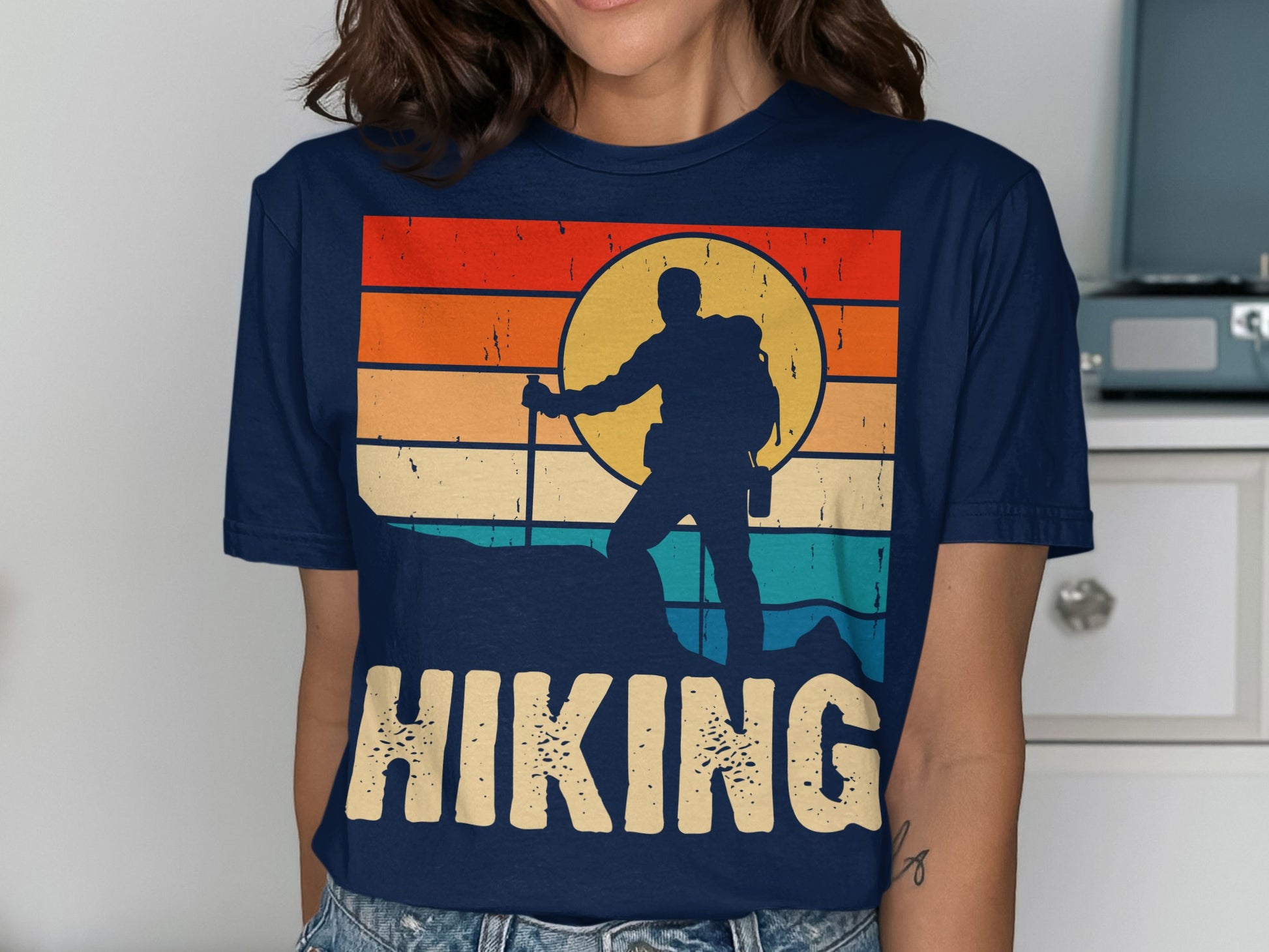 Retro sunset graphic with hiker silhouette and "HIKING" text on a navy t-shirt.