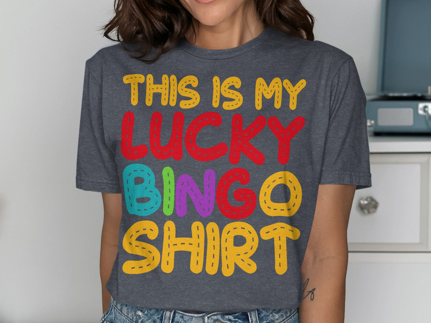 Woman wearing a dark grey t-shirt with colorful "THIS IS MY LUCKY BINGO SHIRT" text.