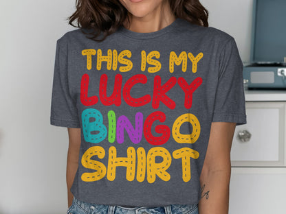 Woman wearing a dark grey t-shirt with colorful "THIS IS MY LUCKY BINGO SHIRT" text.