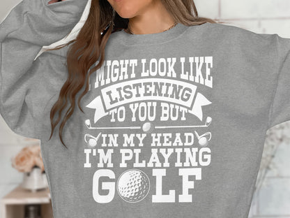 Grey sweatshirt with "Might look like listening to you but I'm playing GOLF" text and golf ball imagery.
