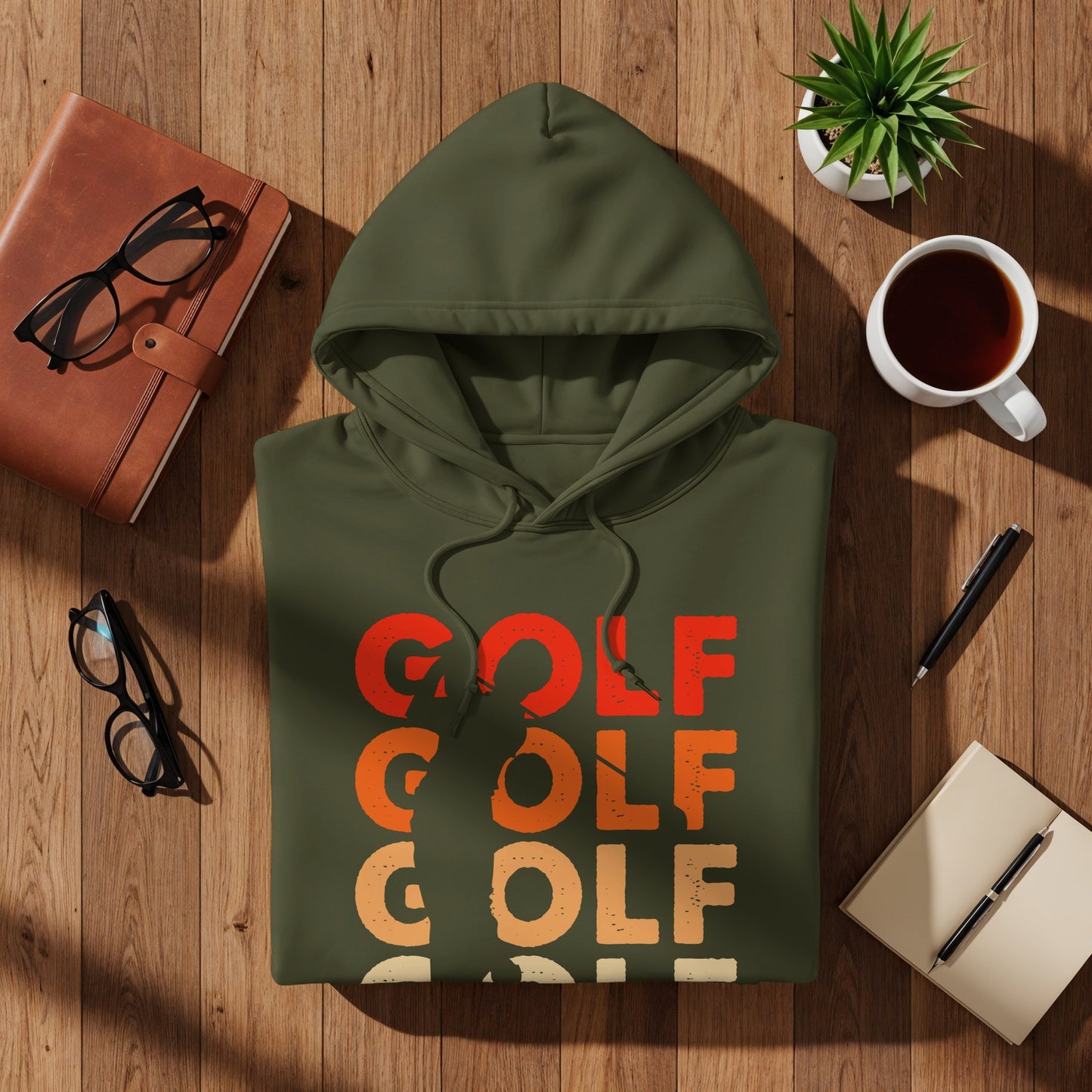 Olive green hoodie with "GOLF" text in red, orange, and beige on a wooden surface.