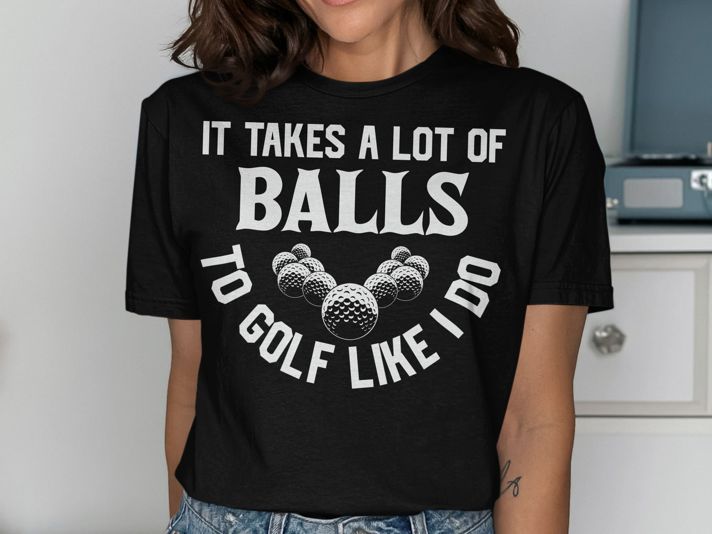 Black t-shirt with "It takes a lot of balls to golf like I do" and golf balls.