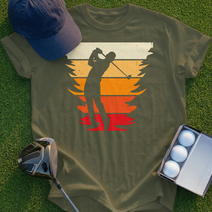 Silhouette of golfer mid-swing against a retro sunset design on a khaki t-shirt.