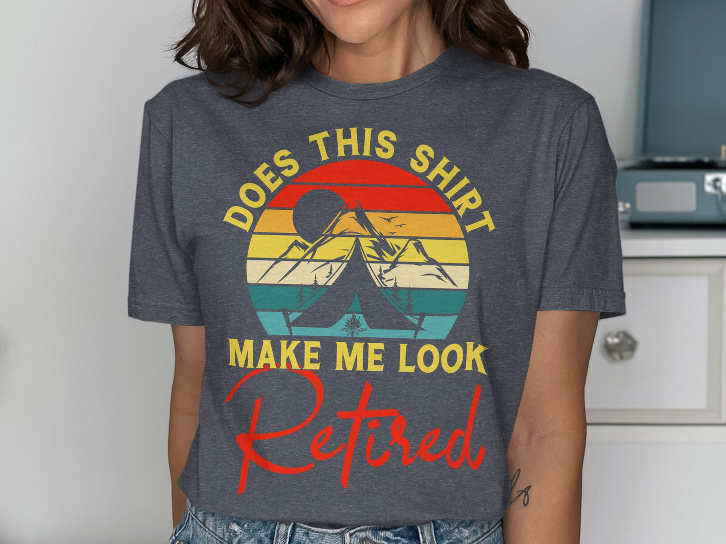 Dark t-shirt with text "DOES THIS SHIRT MAKE ME LOOK RETIRED" and mountain sunset graphic.