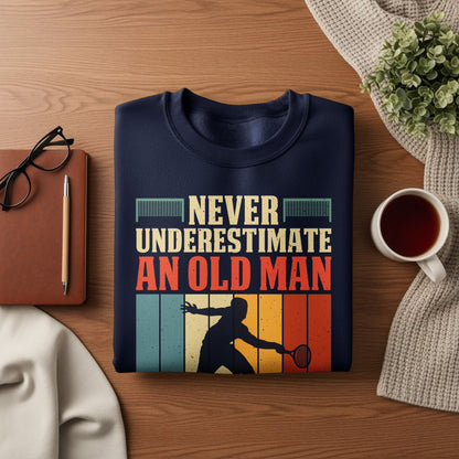 Navy sweatshirt with text "NEVER UNDERESTIMATE AN OLD MAN" and tennis player graphic.