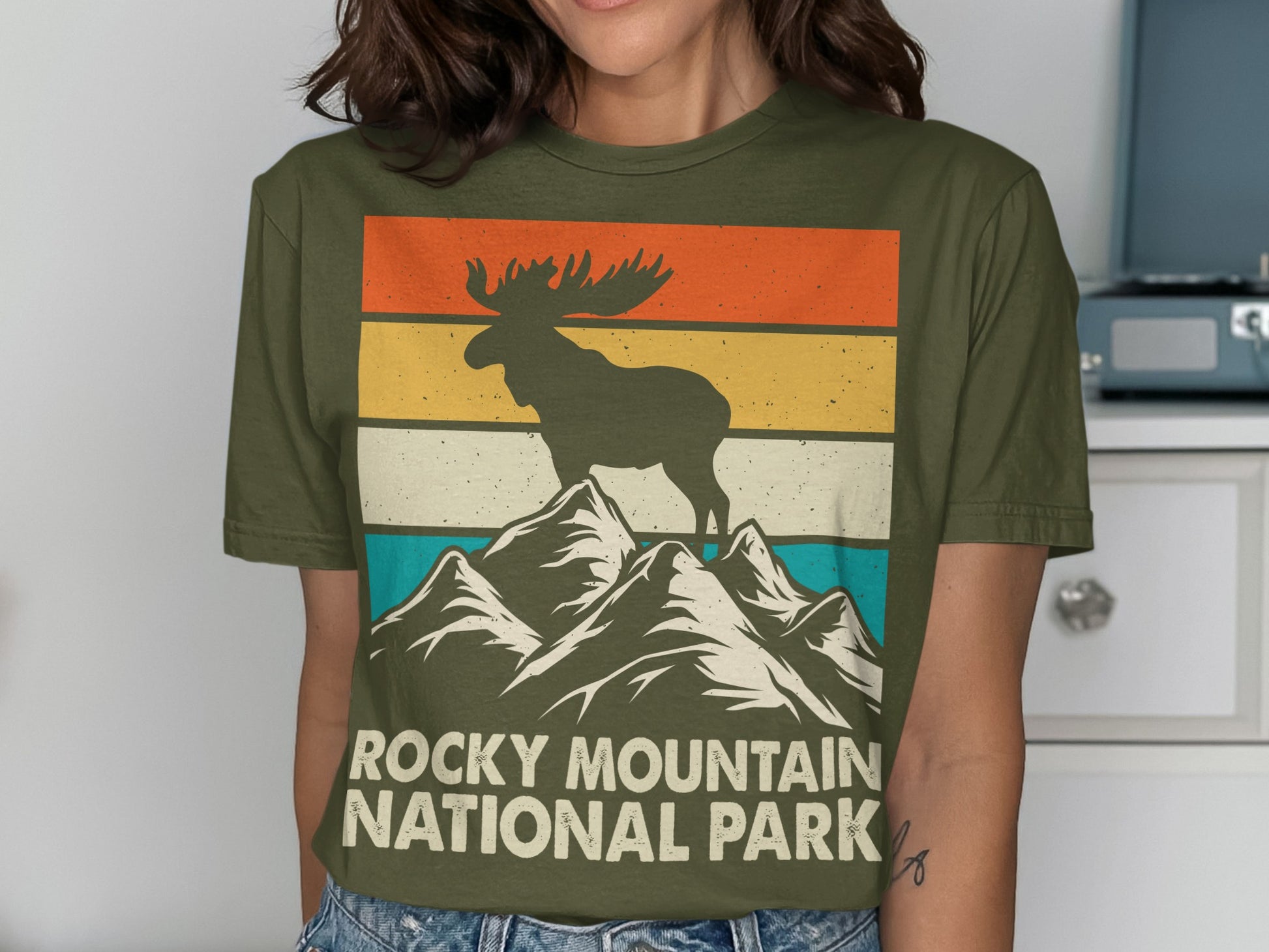 Moose on mountain peak with "Rocky Mountain National Park" text.