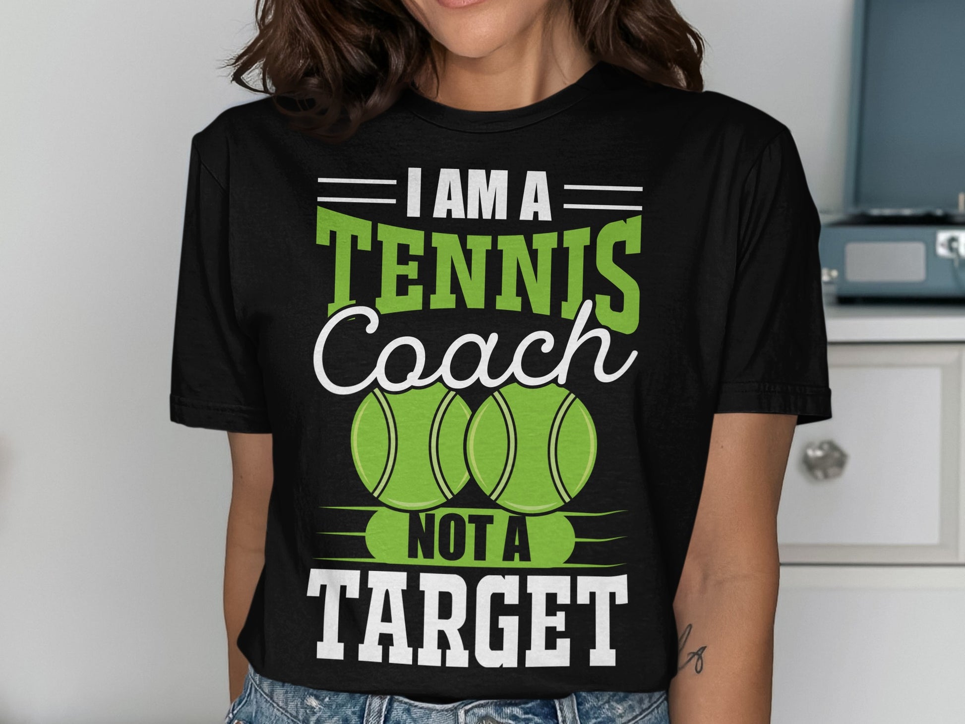 Black t-shirt with "I Am A Tennis Coach Not A Target" text and tennis balls.