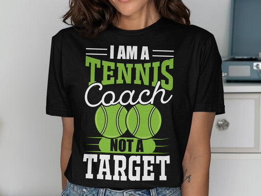 Black t-shirt with "I Am A Tennis Coach Not A Target" text and tennis balls.
