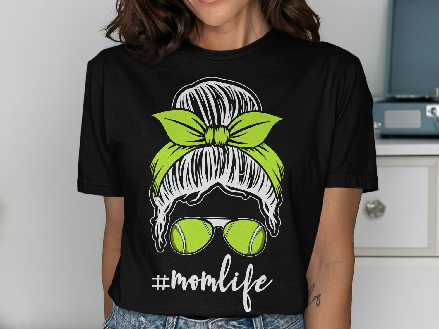 Black t-shirt with green tennis balls and #momlife graphic.